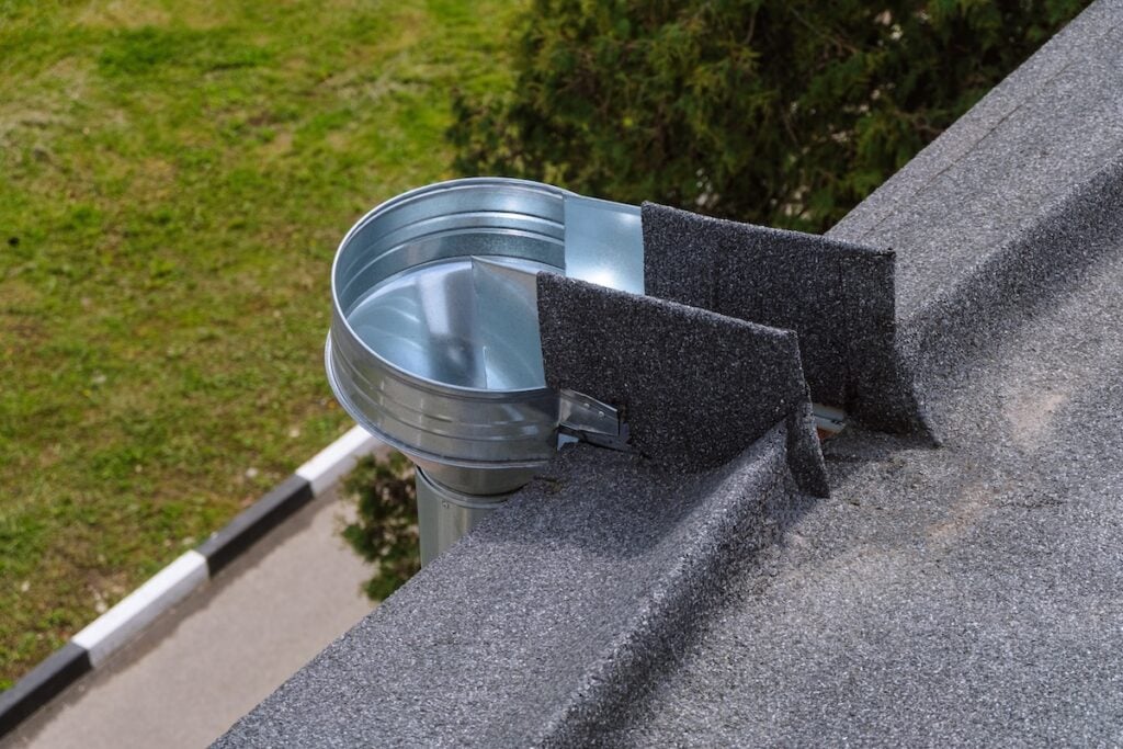 Metal galvanized water inlet funnel on the edge of a soft flat roll roof. External organized drainage system.