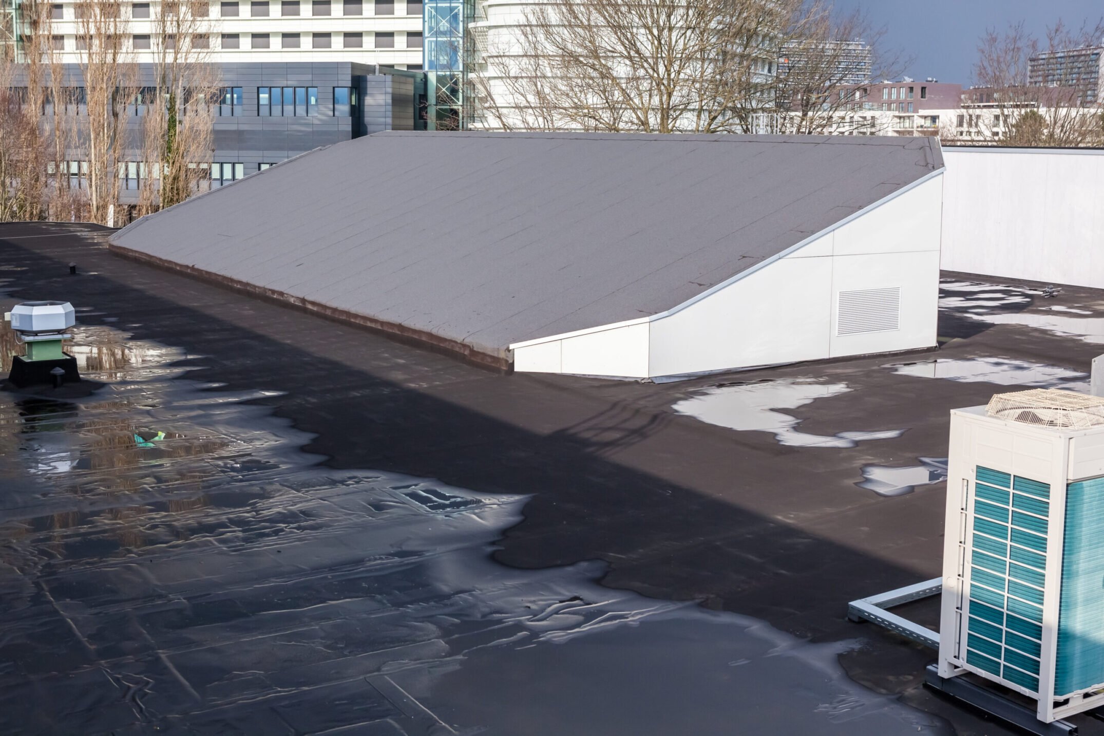 On a large gym building there is a sloping roof with roofing
