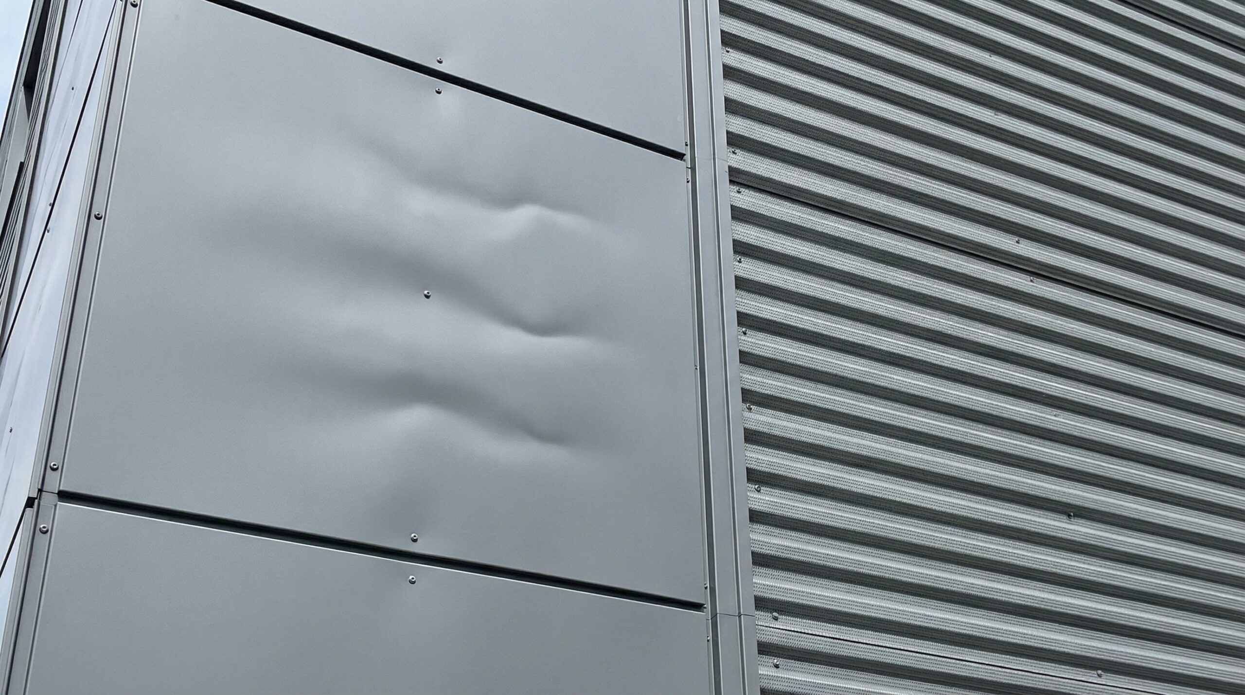 close-up comparison of flat metal panel versus textured panel showing oil canning differences