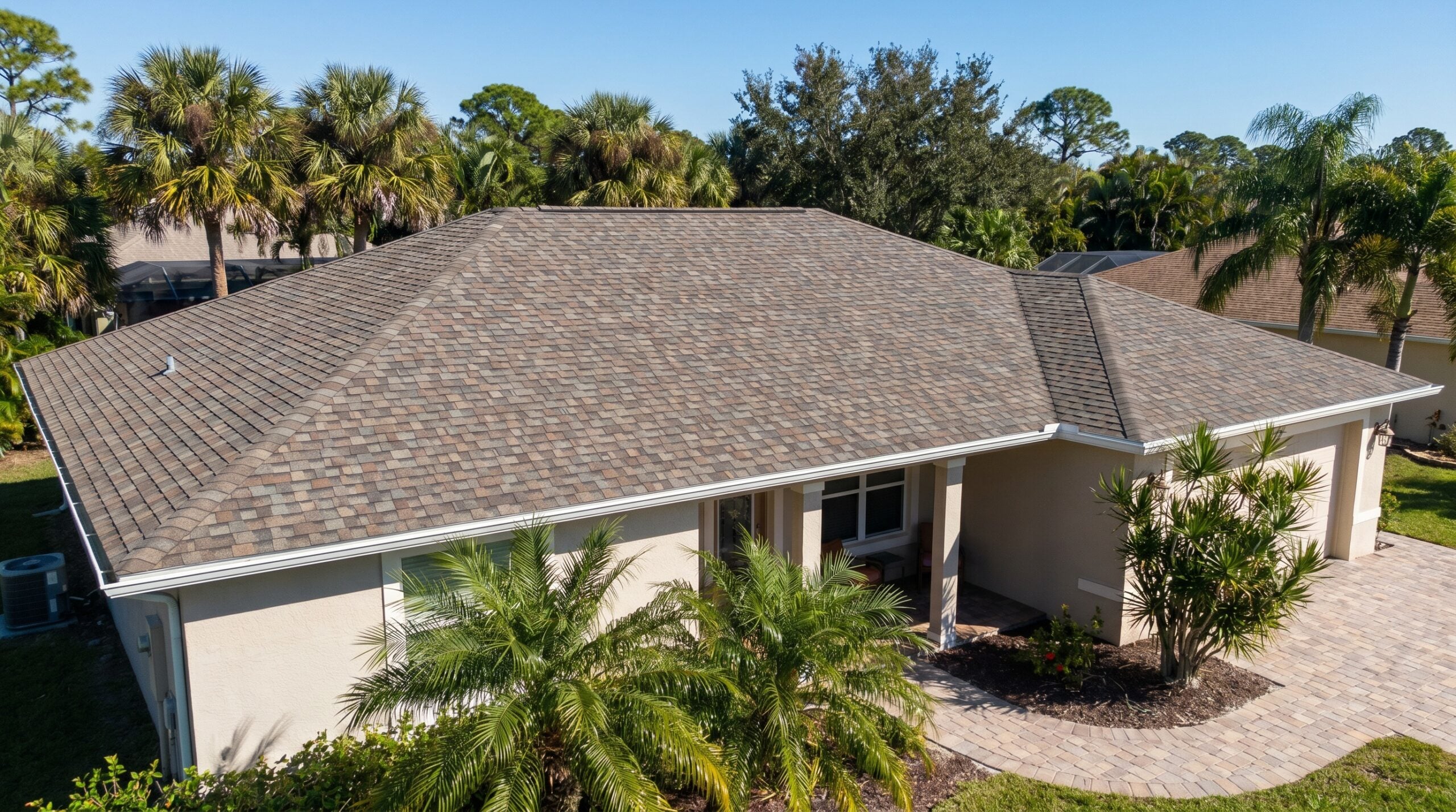 Florida home showing architectural shingles with palm trees in background during sunny weather