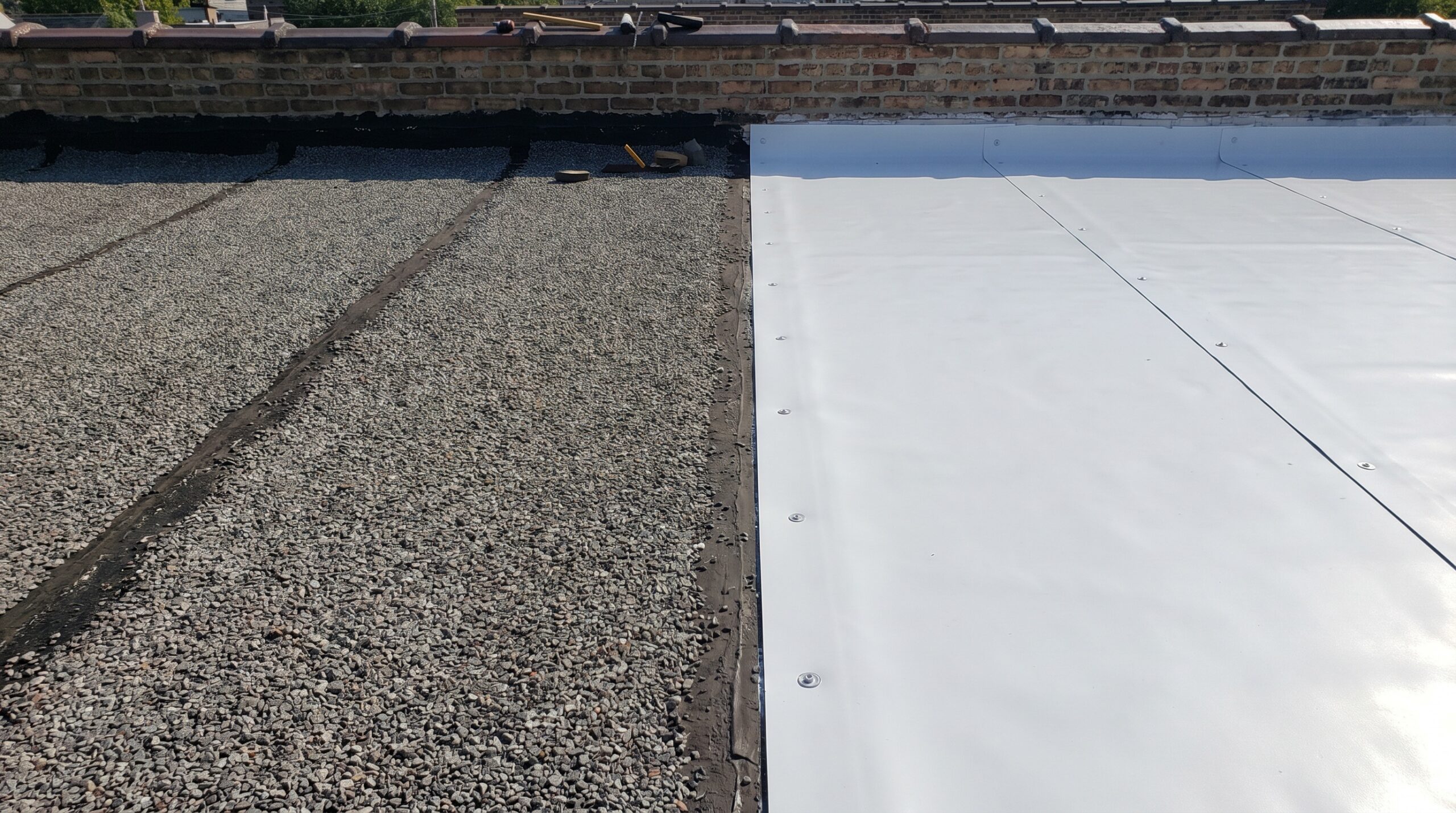 Comparison photo showing gravel-surfaced BUR next to white TPO membrane installation
