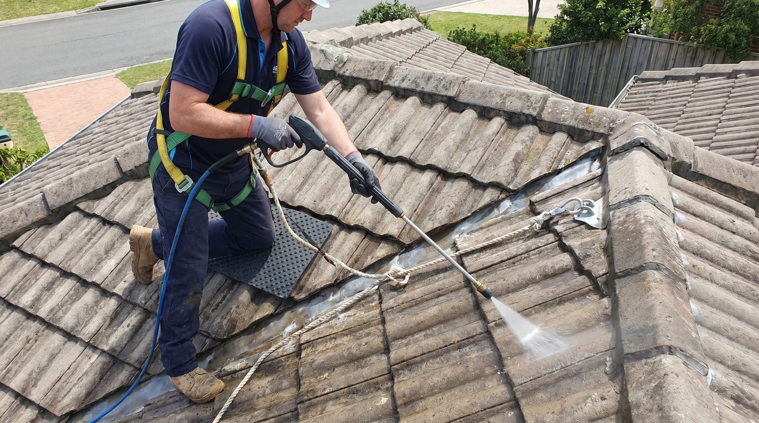 Professional roofer pressure washing concrete tiles safely