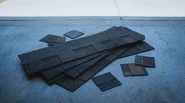 Architectural asphalt shingles from top shingle brands laid out on a concrete garage floor